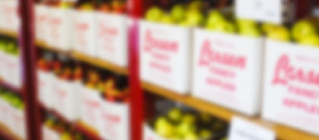 Blurry image of boxes of fresh food on shelves shelves in a wholesale warehouse.