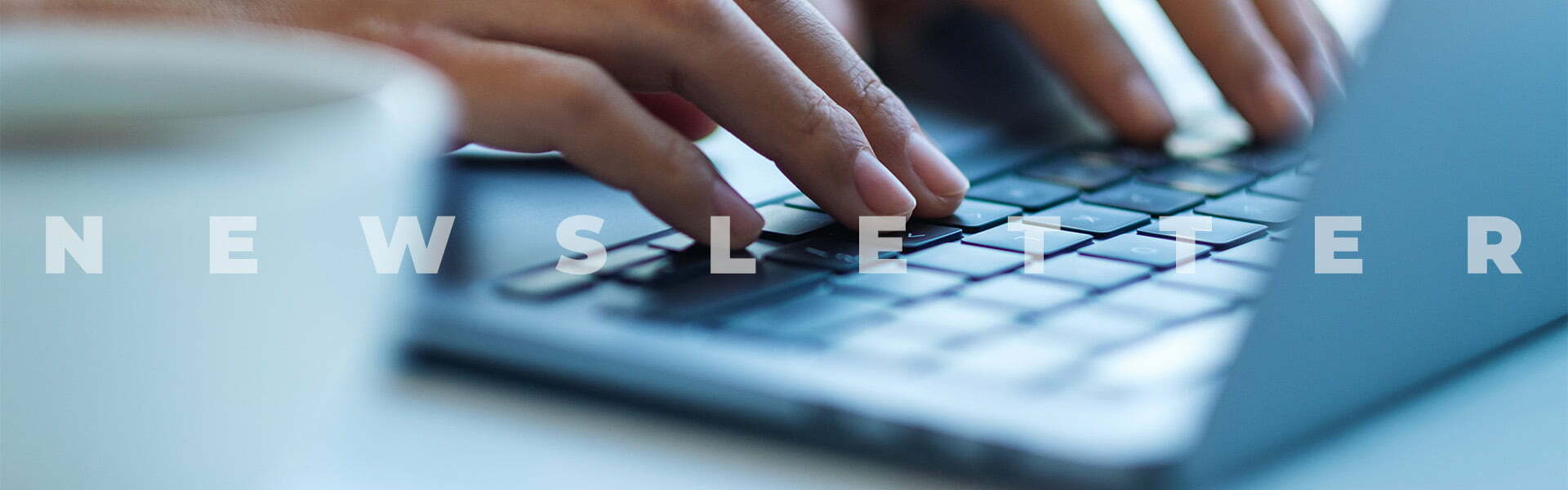 Closeup of a person typing on a laptop with text that says "Newsletter."
